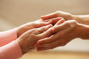 Spotting Elder Abuse And Neglect - Old and young holding hands on light background